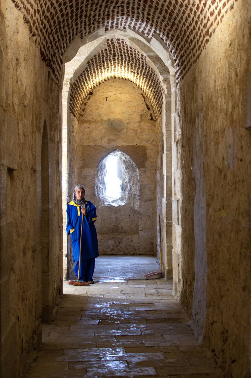 Woman with a broom in a brick corridor